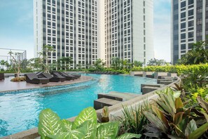 Ein Swimmingpool mit Liegestühlen und Grünflächen, umgeben von hohen Wohngebäuden.