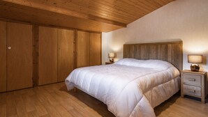 Ein Schlafzimmer mit Holzboden, einem großen Bett, Holzschränken und zwei Nachttischlampen.