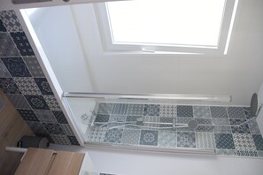 Bathroom features a skylight above the shower, a glass enclosure, and patterned tiles.