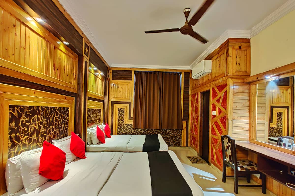 Habitación de hotel con dos camas, un escritorio y un ventilador de techo.