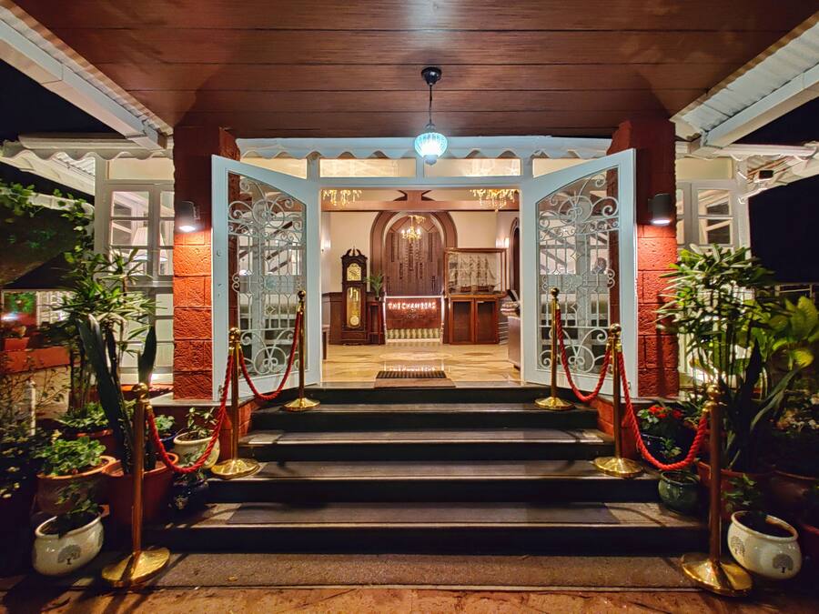 A grand entrance with a wooden staircase leading to a lobby area, featuring a large clock and a ship model display.