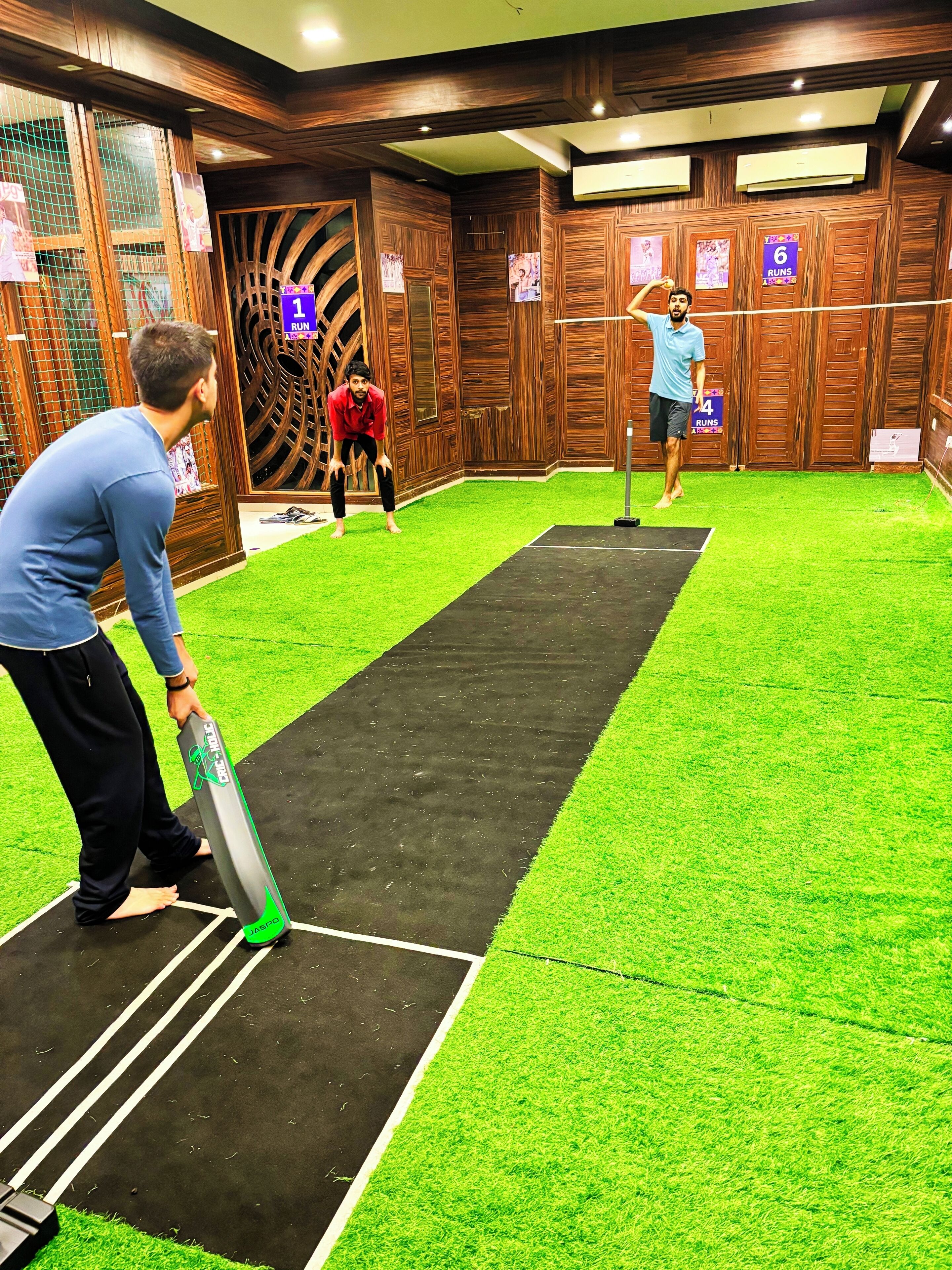 A room with a black mat running through the center, surrounded by green artificial grass.