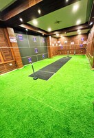Een bowlingbaan met groen kunstgras, houten wanden en nummer genummerde banen.