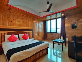 A wooden-paneled bedroom with a bed, a nightstand, a table, and a chair.