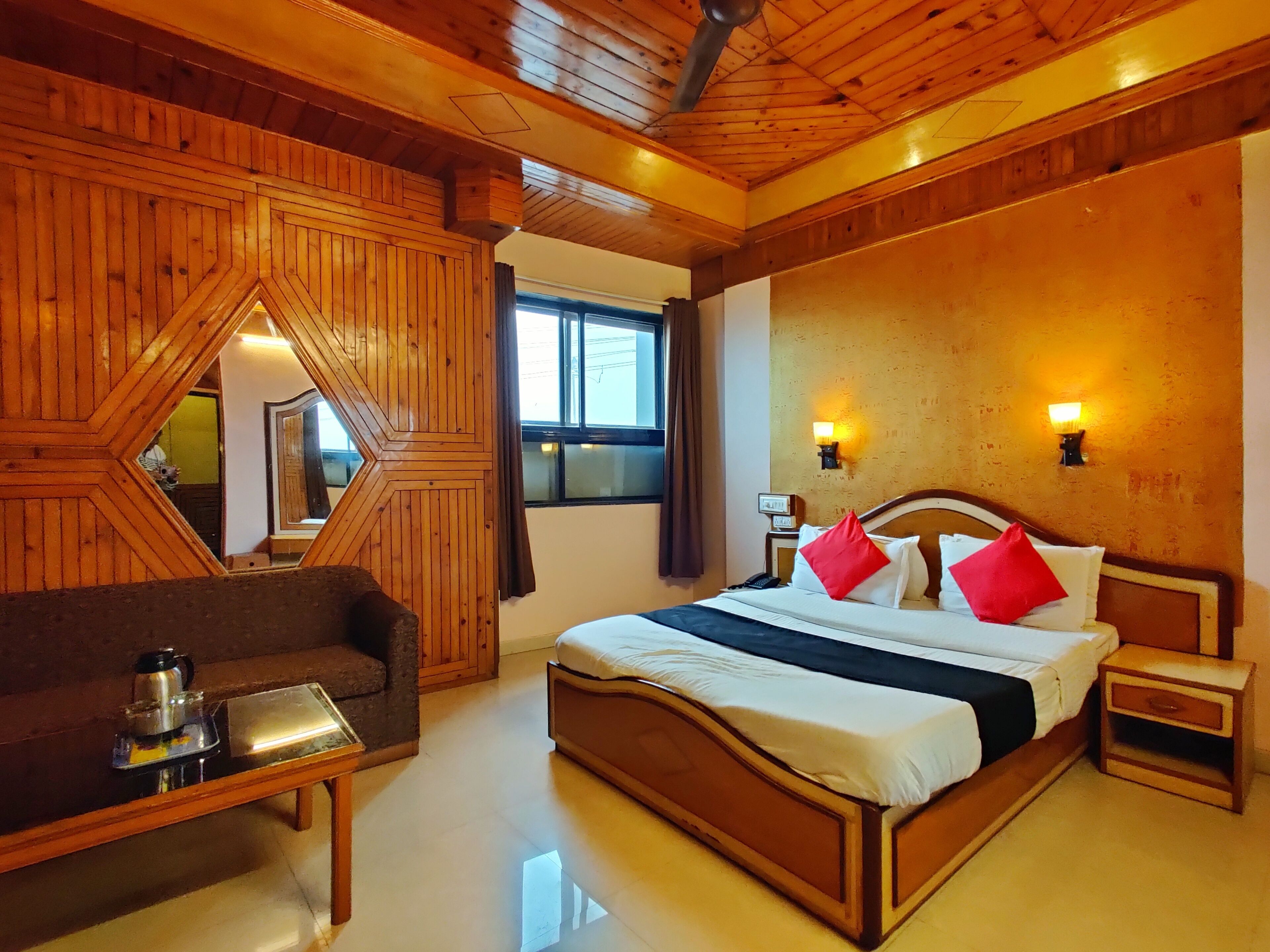A wooden-themed bedroom with a bed, bedside tables, a nightstand, a sofa, and a coffee table.