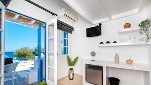 Una sala de estar moderna con un ventanal grande, un televisor de pantalla plana, chimenea y un balcón con mobiliario exterior.