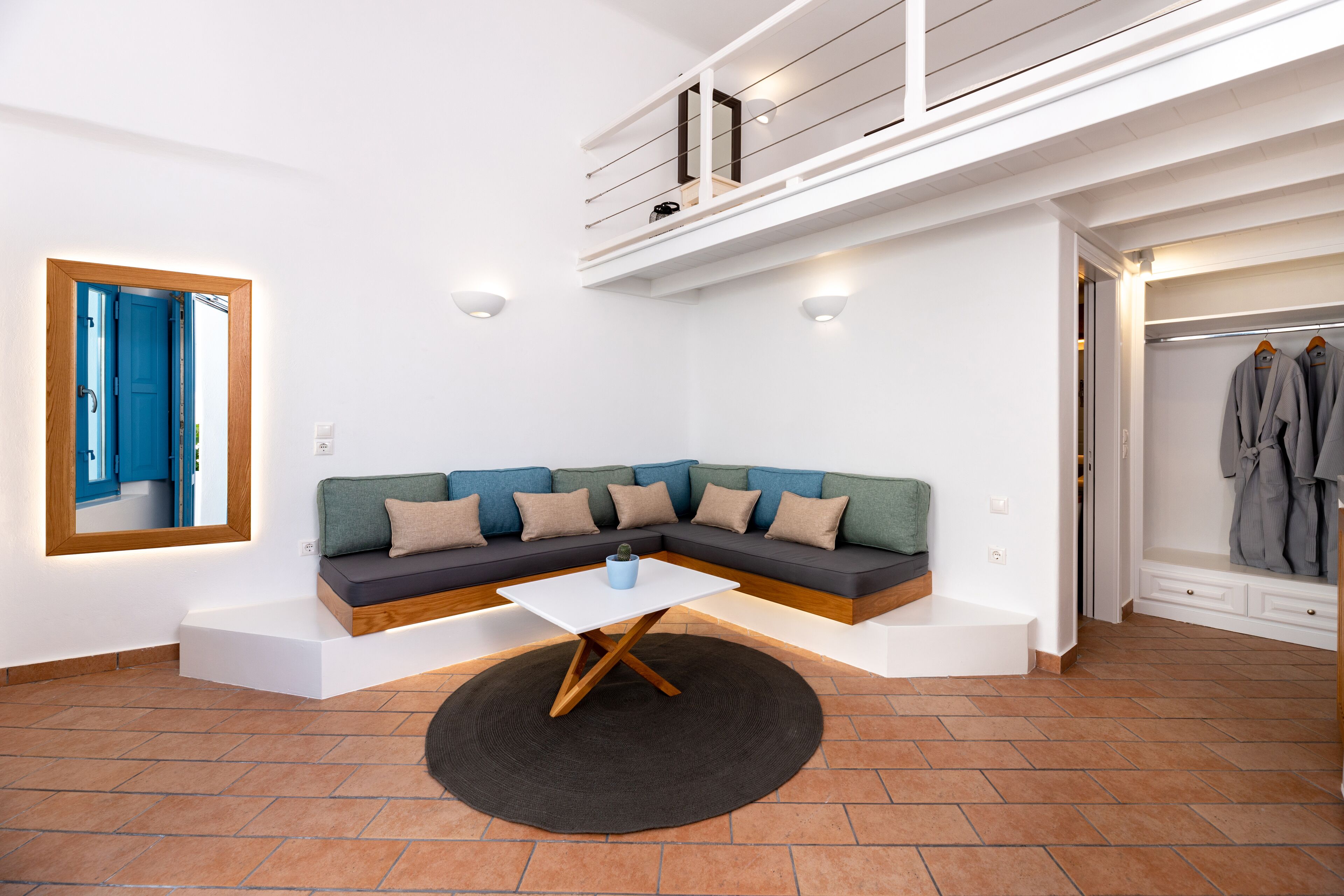 A modern living room with a sectional sofa, a coffee table, and a built-in closet with hanging clothes.