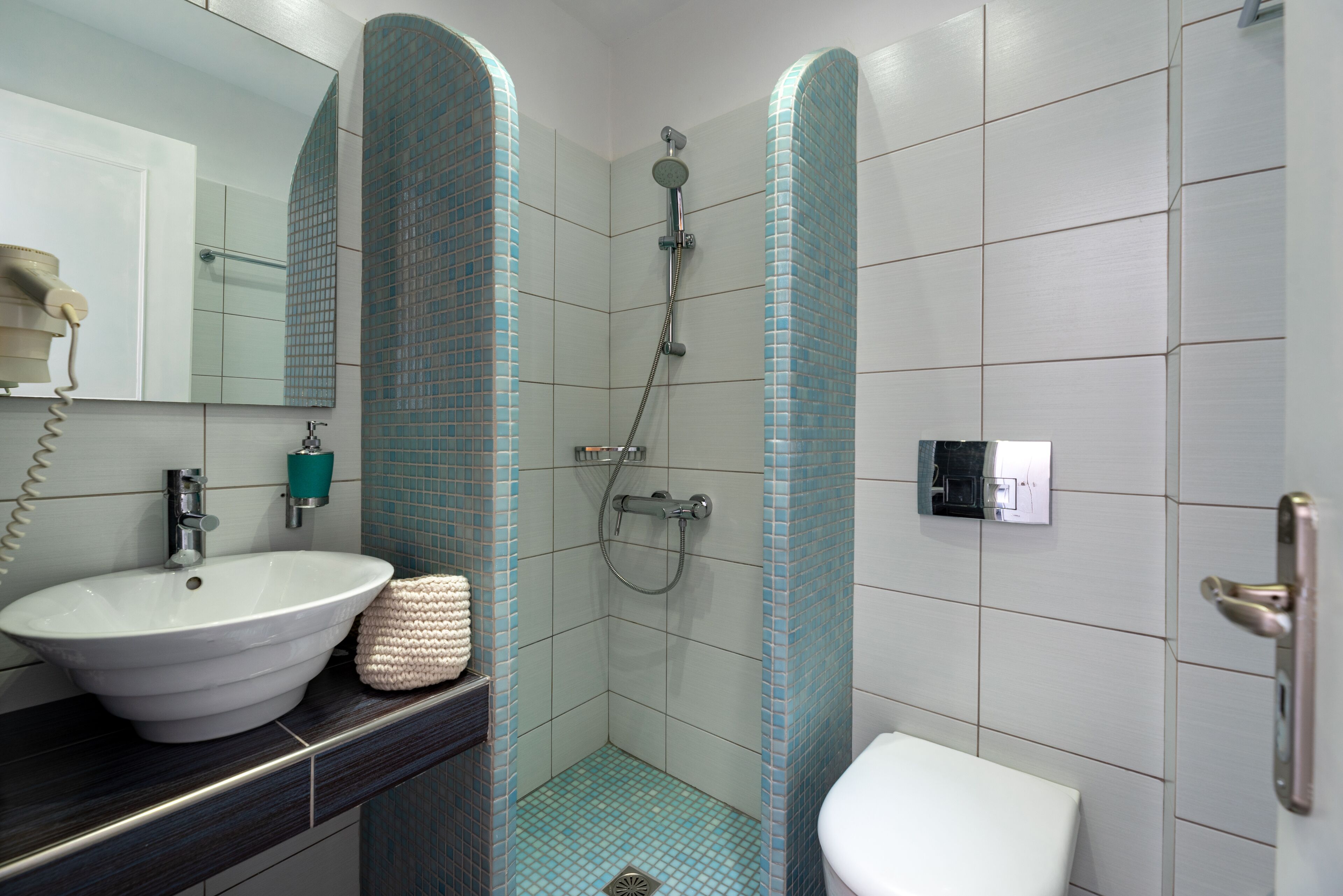 A bathroom with a white sink, a mirror, a towel, a shower, and a toilet.