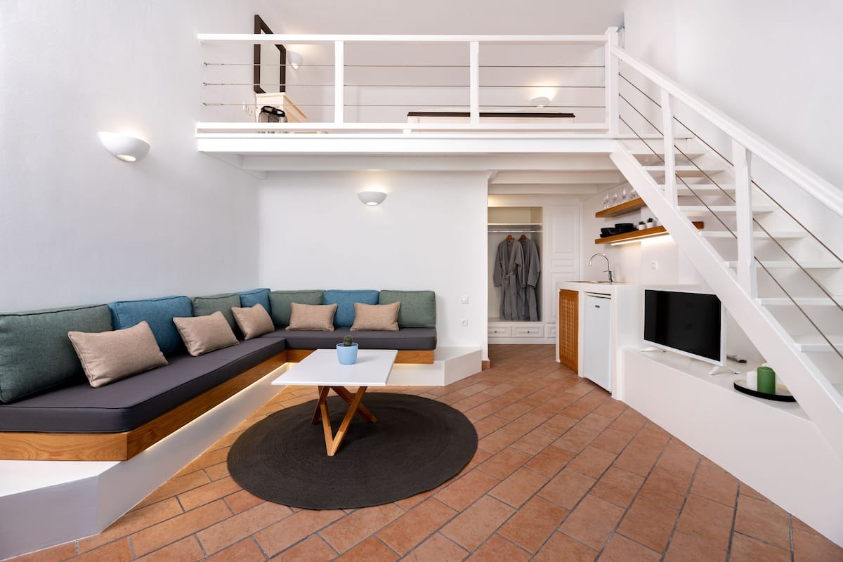 A modern apartment with a loft bedroom, a dining area, and a kitchen.