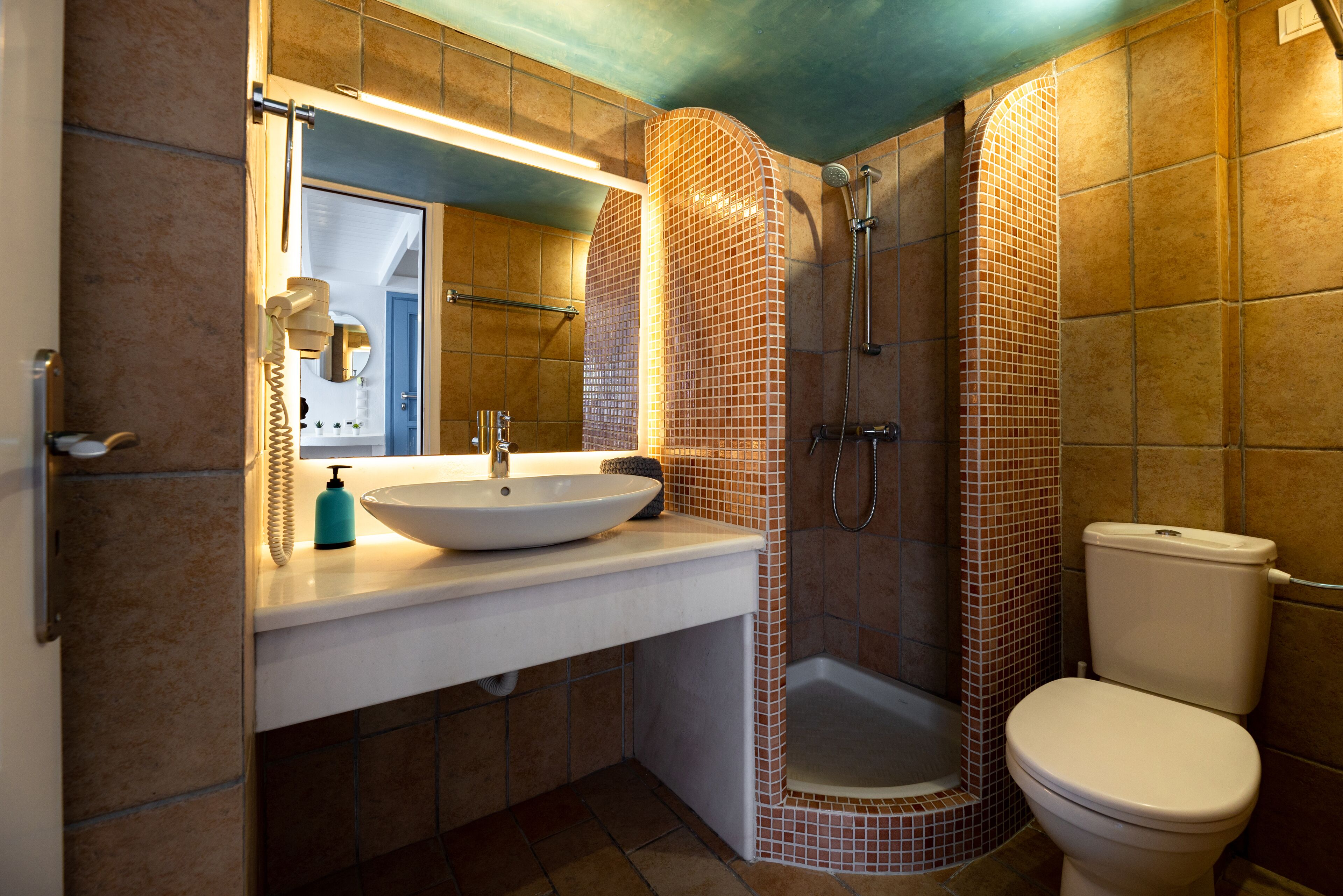 Une salle de bain avec un lavabo blanc, un miroir et des toilettes.