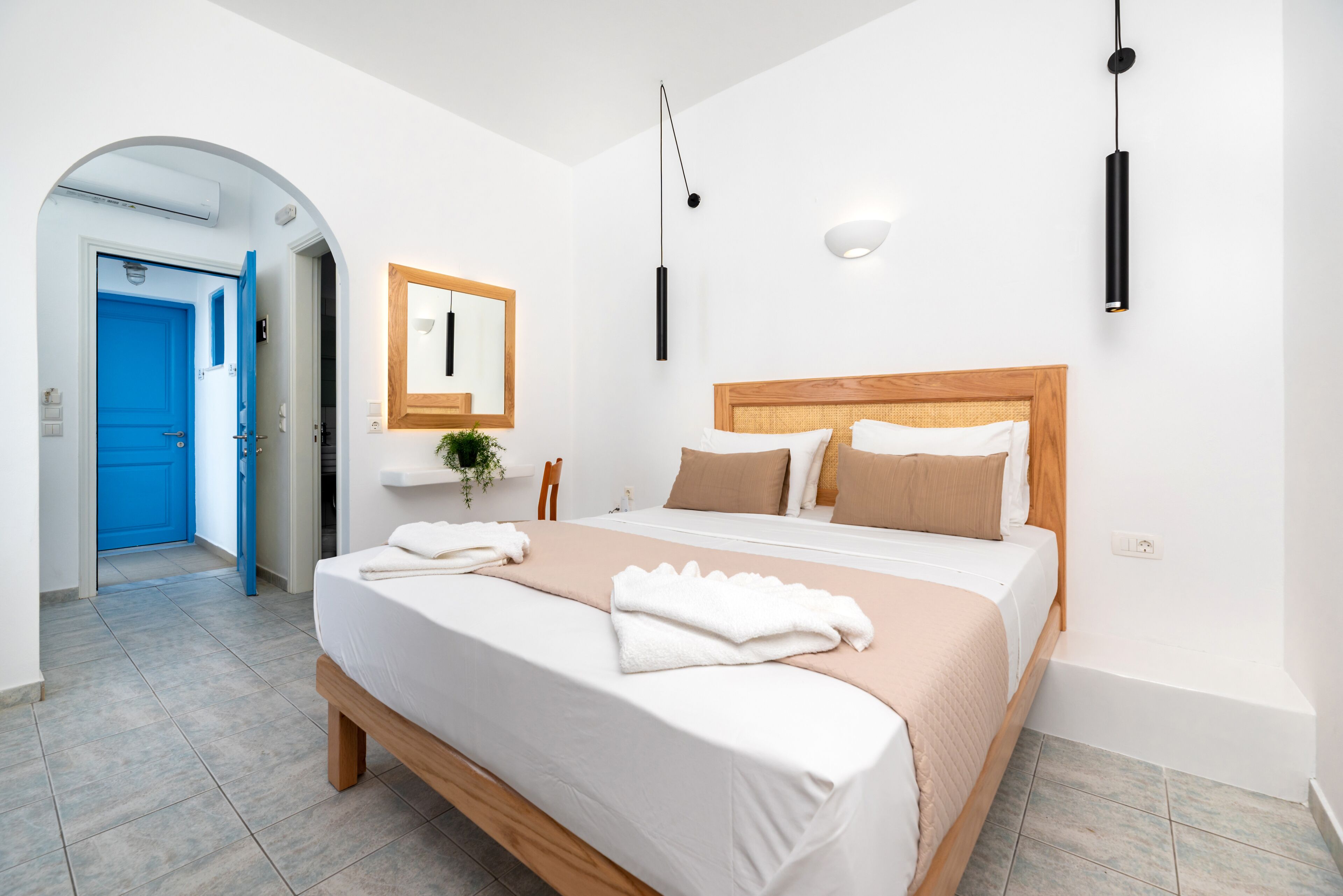 Une chambre à coucher avec un lit, une tête de lit en bois, une table de chevet, un miroir et une porte bleue.