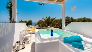 Un área de piscina en la azotea con un jacuzzi, sillas de descanso y vistas al océano.