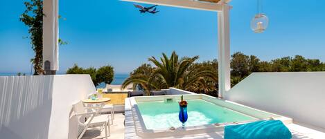 A rooftop pool area with a hot tub, lounge chairs, and a view of the ocean.