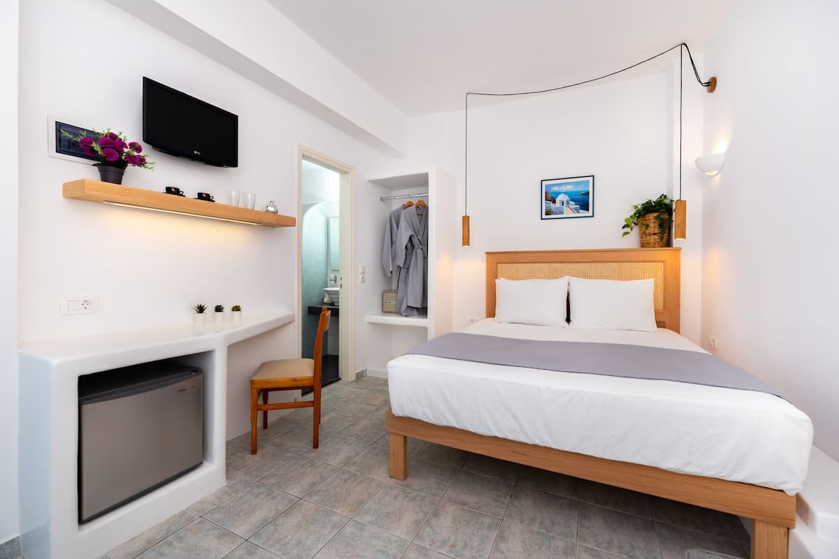 A modern bedroom with a bed, a TV, a small desk, and a chair.