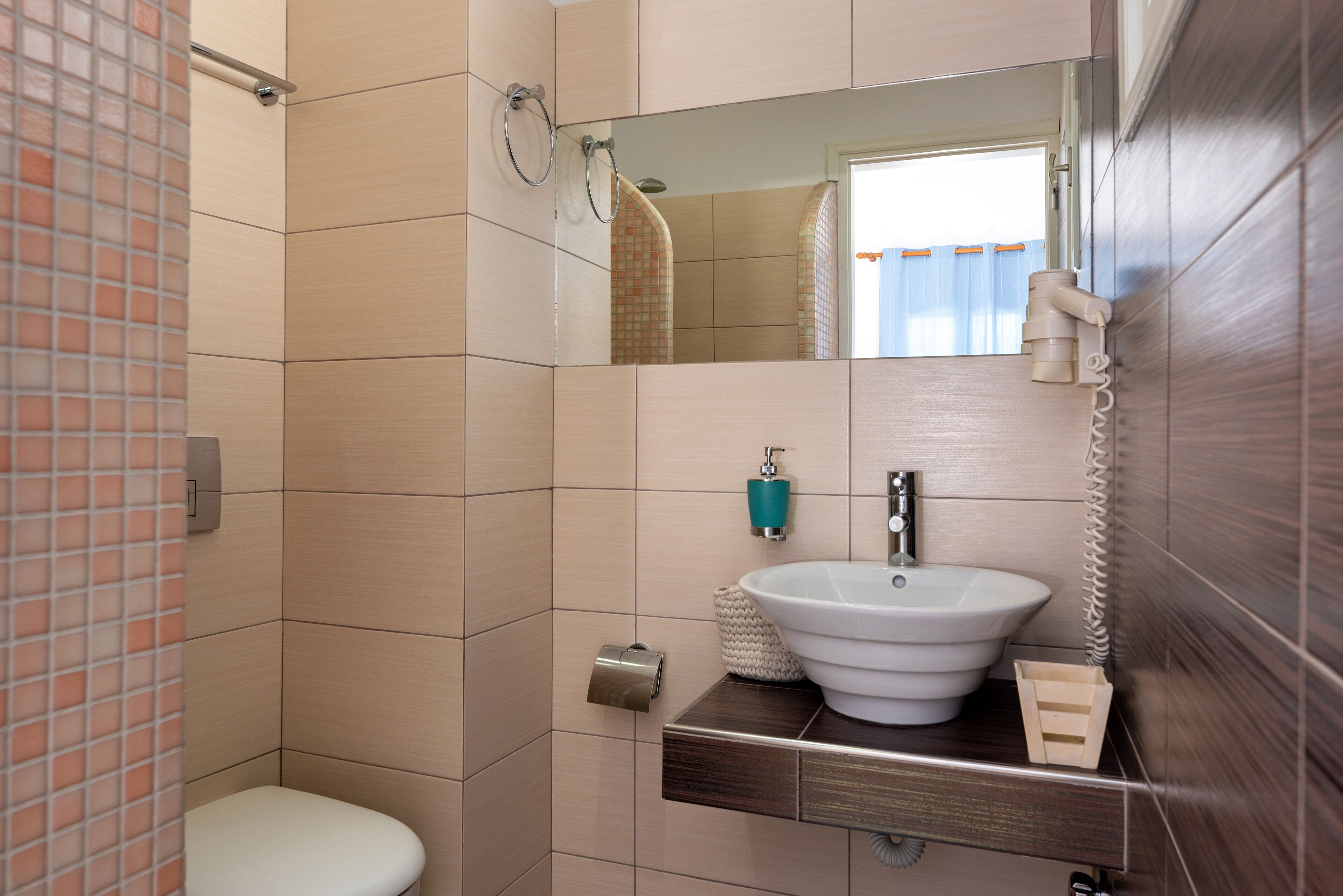 A bathroom with a toilet, sink, mirror, and towel rack.