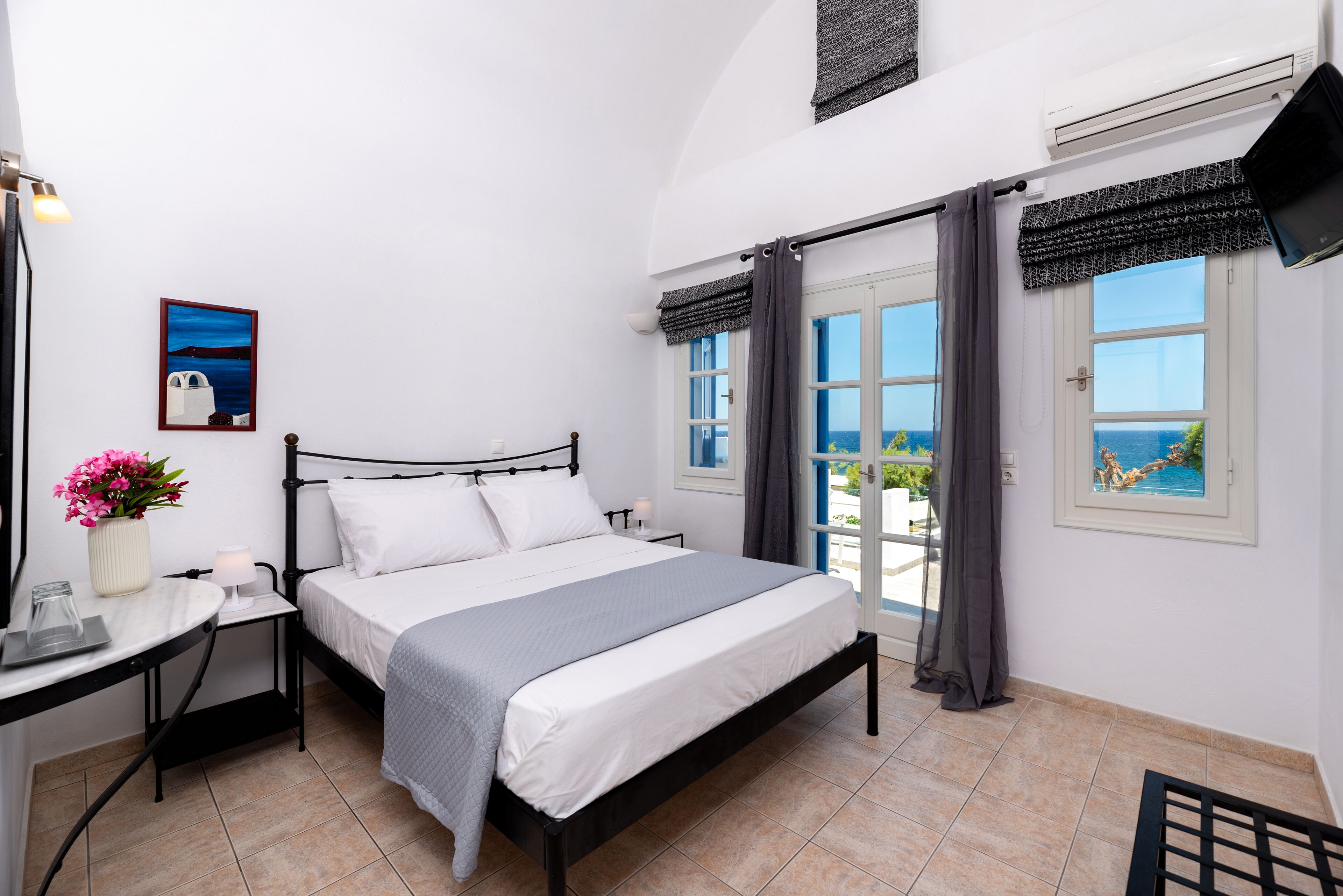 A bedroom with a bed, bedside table, lamp, and a painting on the wall.