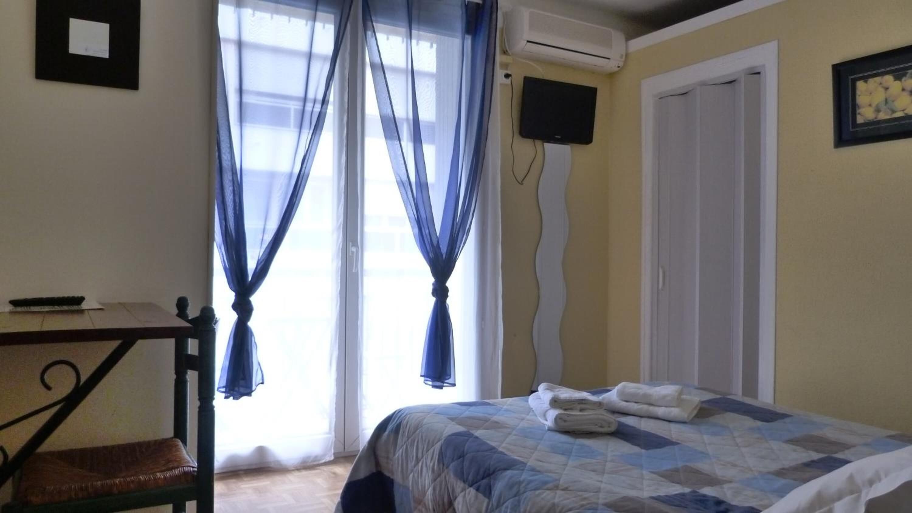 Une chambre à coucher comprenant un lit, un bureau, une chaise, un téléviseur et un appareil de climatisation.