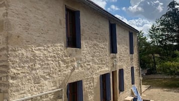A stone building with multiple windows and a fenced area.