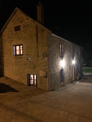 Un edificio de piedra con varias ventanas, algunas iluminadas durante la noche.
