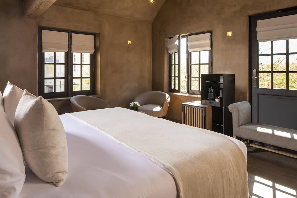 A bedroom with a large bed, two chairs, a small table, and a TV.