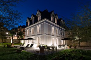 A large, illuminated building with a symmetrical facade, multiple windows, and a well-maintained garden with outdoor seating. - Hôtel Saint-Delis & Spa - Relais & Châteaux (Honfleur)