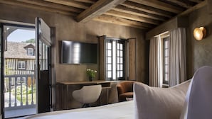 Une chambre à coucher comprenant un lit, un bureau, une chaise, un téléviseur et donnant sur l’extérieur.