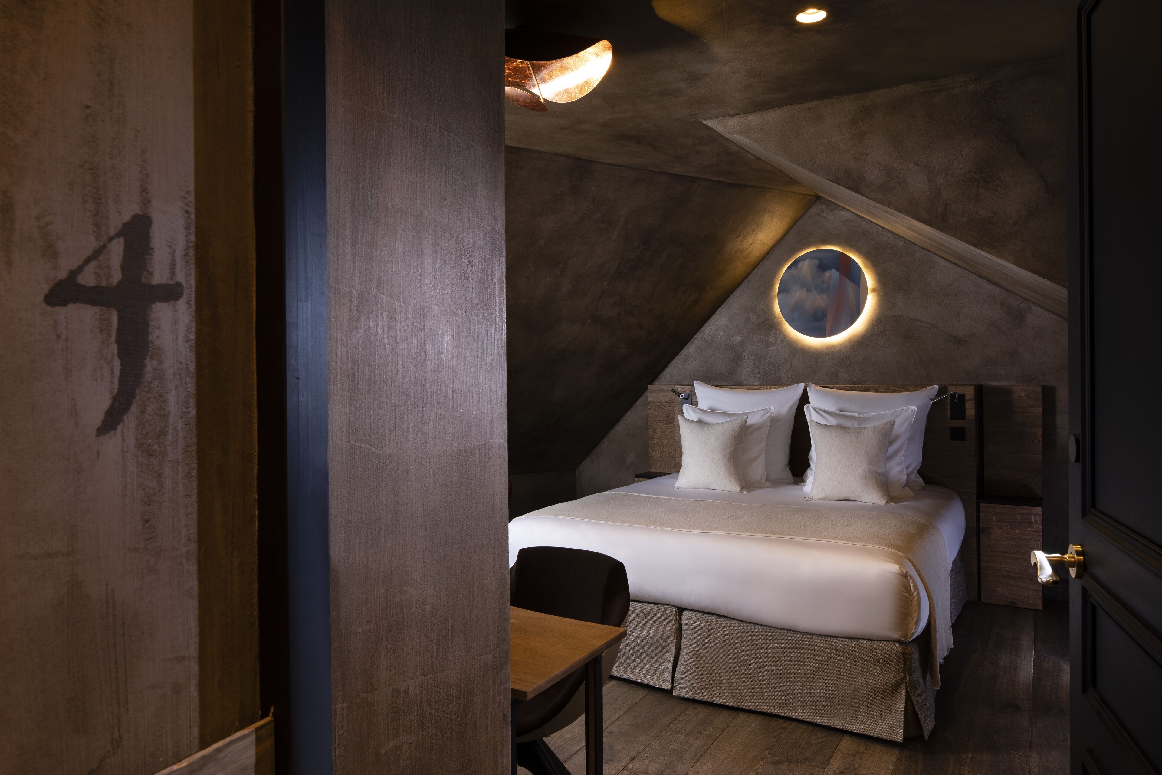 A modern bedroom with a large bed, a desk, and a circular skylight.