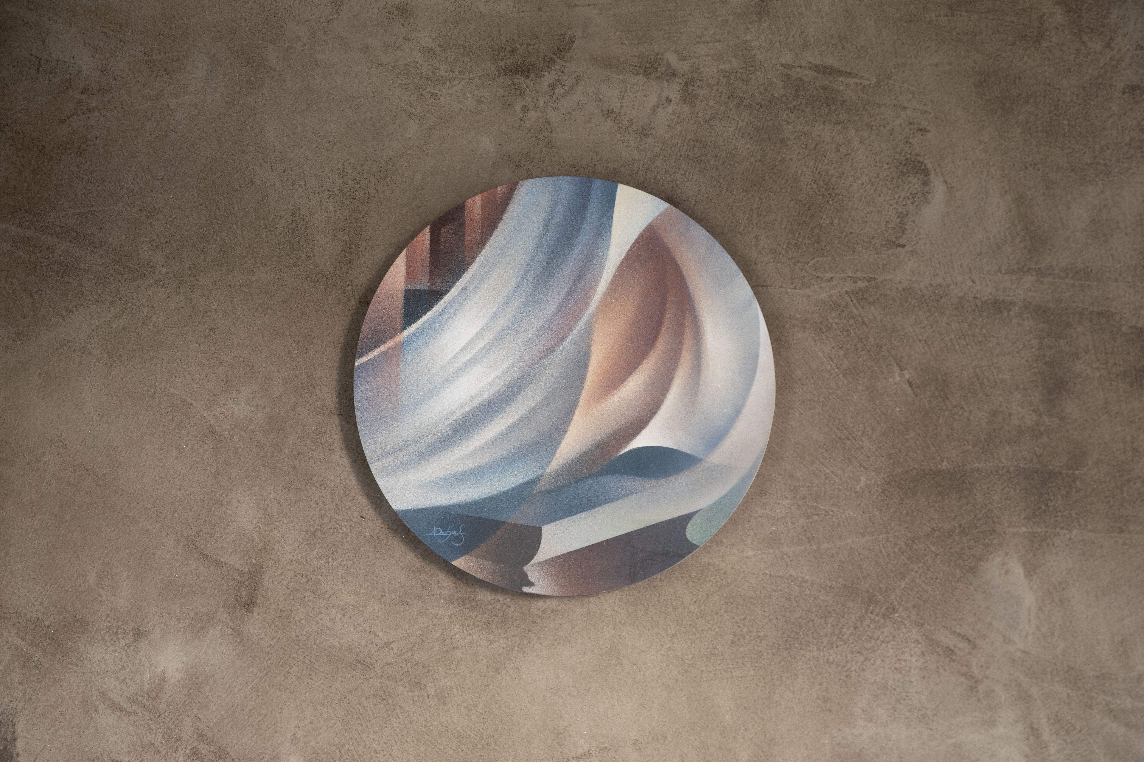 Una obra de arte circular con patrones abstractos sobre una pared texturizada.