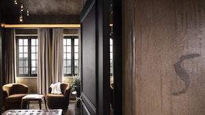 Une pièce dotée d’une grande fenêtre, de deux fauteuils, d’une petite table et d’un pouf en cuir.