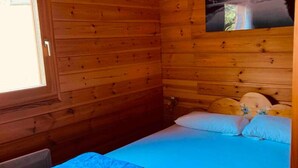 Ein Holzhütten-Zimmer mit einem Bett, einem Fenster und einem Bild an der Wand.