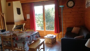 Ein gemütliches Zimmer mit Holzeinrichtung, einem Esstisch mit Stühlen, einer Couch und einer Uhr an der Wand.