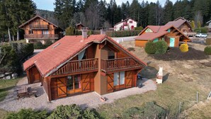 Eine Holzhütte mit Balkon, einem Schotterweg und umliegenden Bäumen.