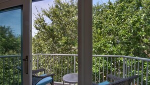 A balcony with wicker furniture and a small table, surrounded by a white railing. - Sonrise Retreat - Hosted By Moore AI Rentals (Fernandina Beach)
