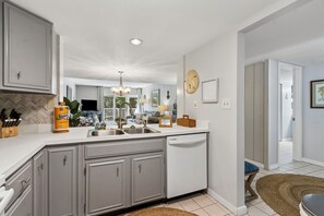 A modern kitchen with grey cabinets, a stainless steel sink, and a dishwasher.