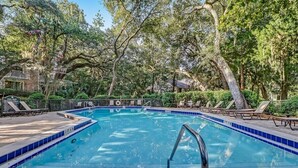 A rectangular swimming pool with a blue tiled edge, surrounded by lounge chairs and trees. - Sonrise Retreat - Hosted By Moore AI Rentals (Fernandina Beach)