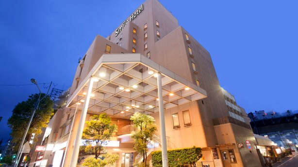 Un hotel con diseño moderno, que destaca por una entrada con galería techada y un cartel que dice "Smile Hotel".
