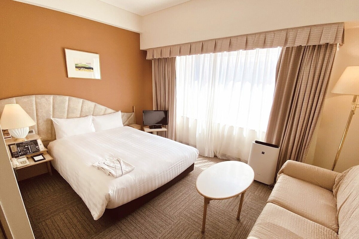 Una habitación de hotel con cama, mesita de noche, televisor y una pequeña mesa redonda.