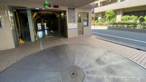 Fachada de edificio con azulejos, un corredor cubierto y un paraguas de metal.