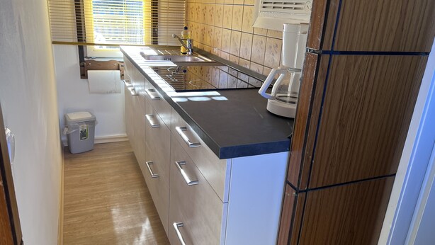 Een kleine keuken met een spoelbak, fornuis en koffiezetapparaat.