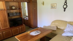 Een woonkamer met een houten tv-meubel, een beige bank en een houten salontafel.