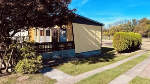 Yhden kerroksen talo, jossa on kuisti, pieni puutarha ja hyvin hoidettu nurmikko.