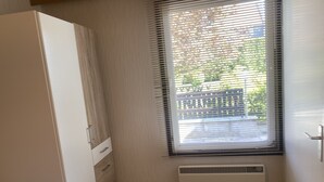 Een kamer met een witte kast, een radiator en een raam met zonwering.