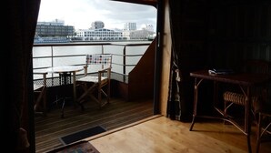 Una stanza con vista sul fiume e sugli edifici, un tavolo, due sedie e un pavimento in legno.
