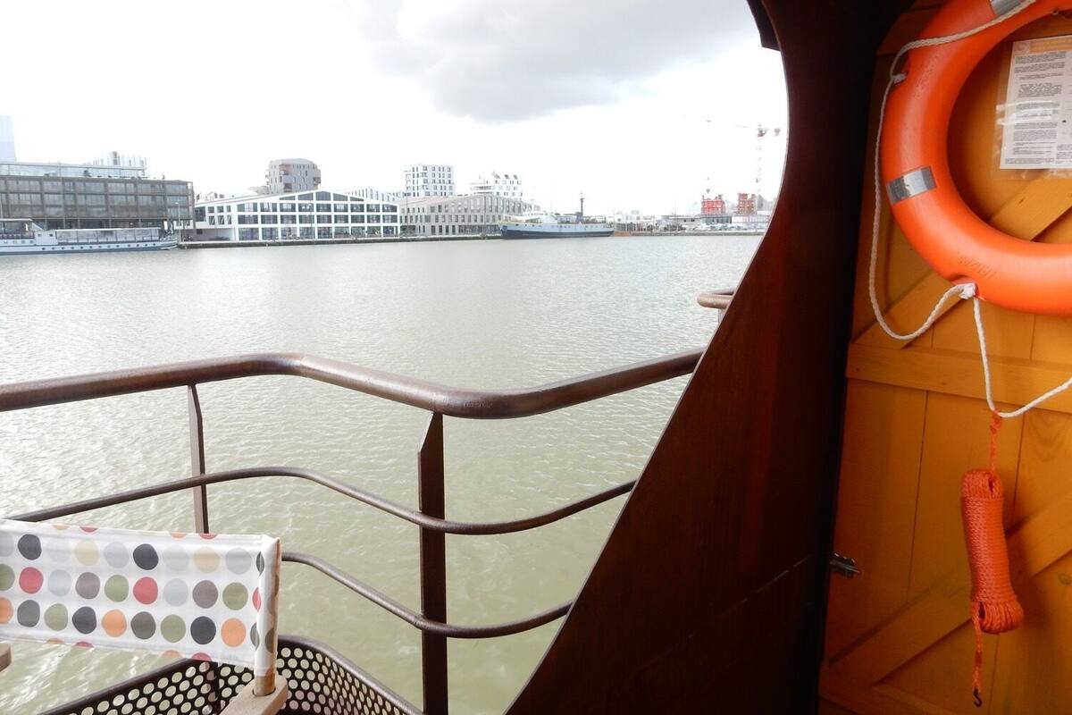 Vue prise depuis le pont d’un bateau, avec un gilet de sauvetage accroché à la rambarde et une table à motifs à pois au premier plan.