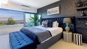 A modern bedroom with a large bed, a view of the city, and a balcony. - Clifton YOLO Spaces – Clifton Beachfront Executive  (Cape Town)