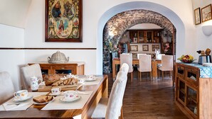 A dining area with a stone archway, wooden furniture, and a large religious painting. - Lubra Casa Relax (Massa lubrense)