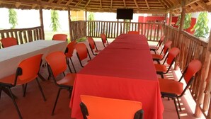 A covered outdoor dining area with a long table and orange chairs. - Florence Hotel Firenze Yamoussoukro (Yamoussoukro)