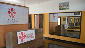 A hotel reception desk with a sign for Florence Hotel, a mirrored wall, and a framed picture of a cityscape. - Florence Hotel Firenze Yamoussoukro (Yamoussoukro)