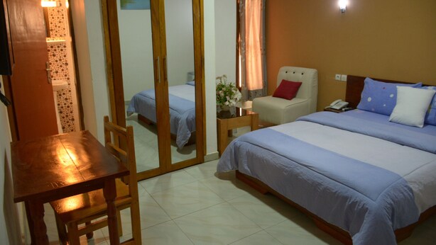 A hotel room with a bed, a chair, a table, and a mirror. - Florence Hotel Firenze Yamoussoukro (Yamoussoukro)