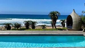 Une terrasse en bois avec une piscine donnant sur l’océan.